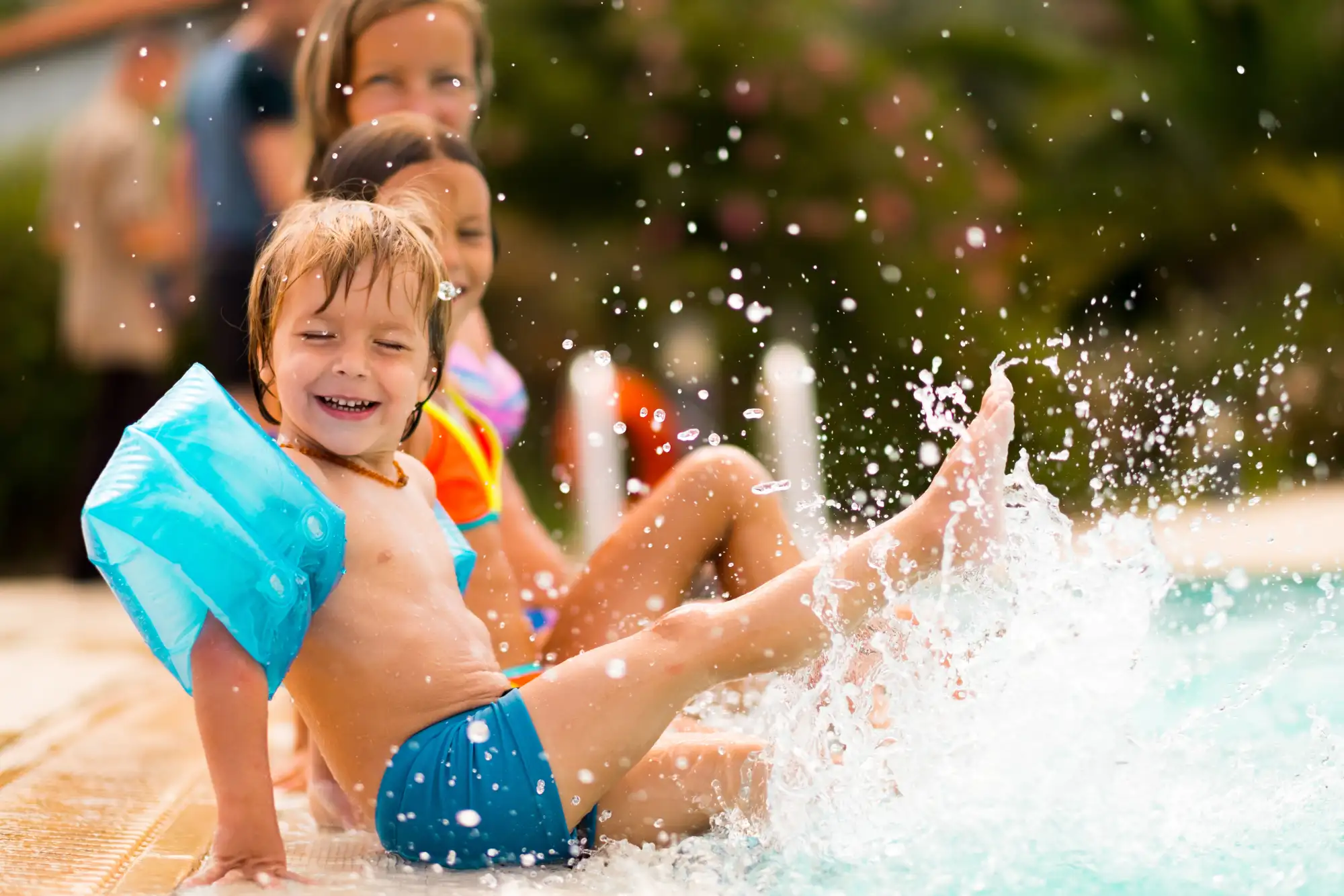 Happy children splashing feet at pool edge in summer