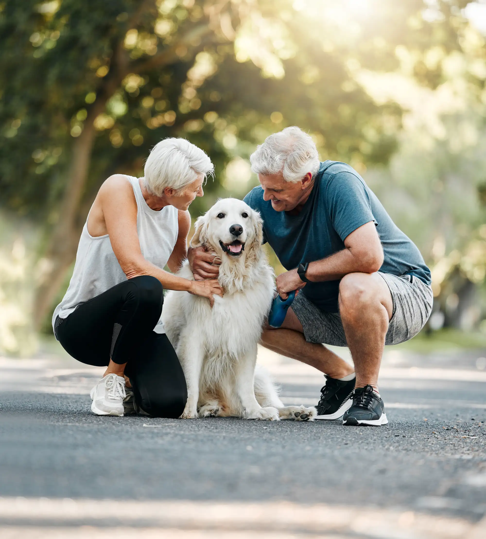 Senior couple in athletic wear petting white dog outdoors