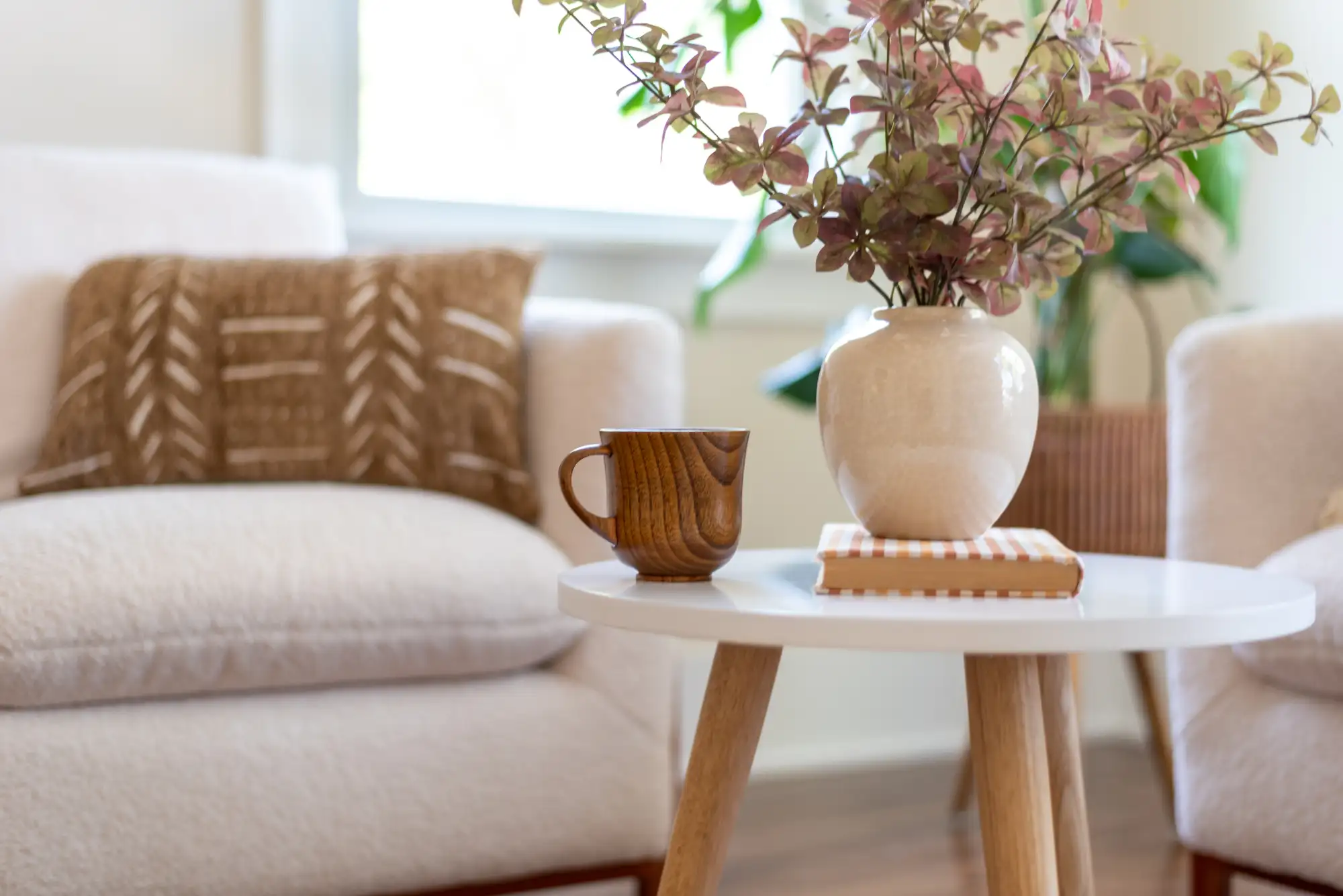 Cozy living room with white side table, vase, and mug