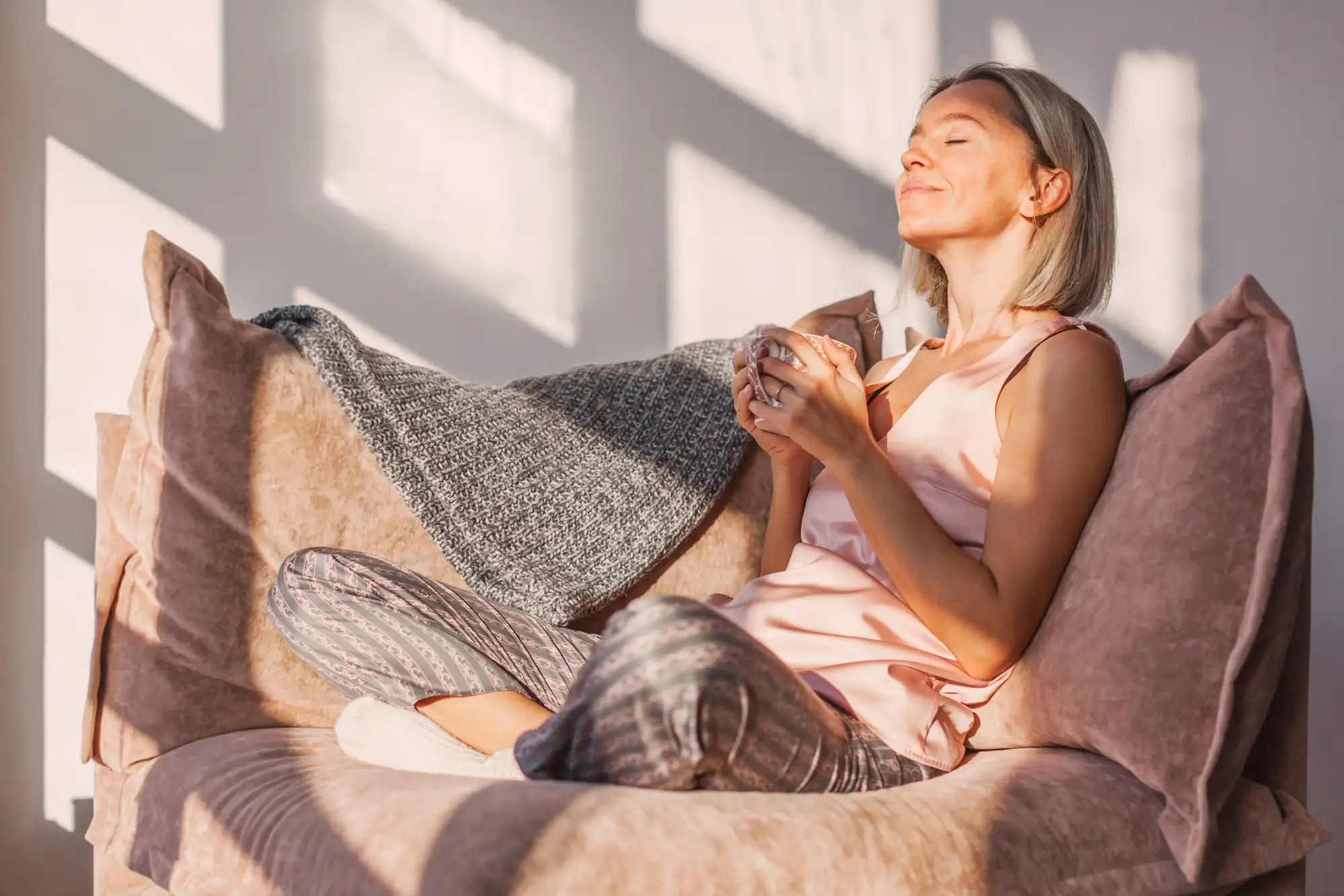 Woman relaxing on couch with coffee cup in sunlight