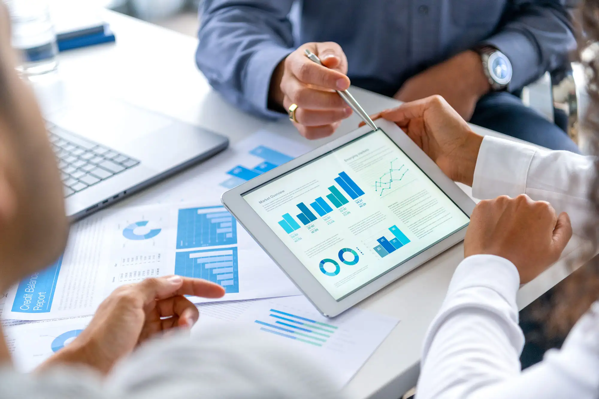 Business professionals reviewing financial charts on tablet during meeting