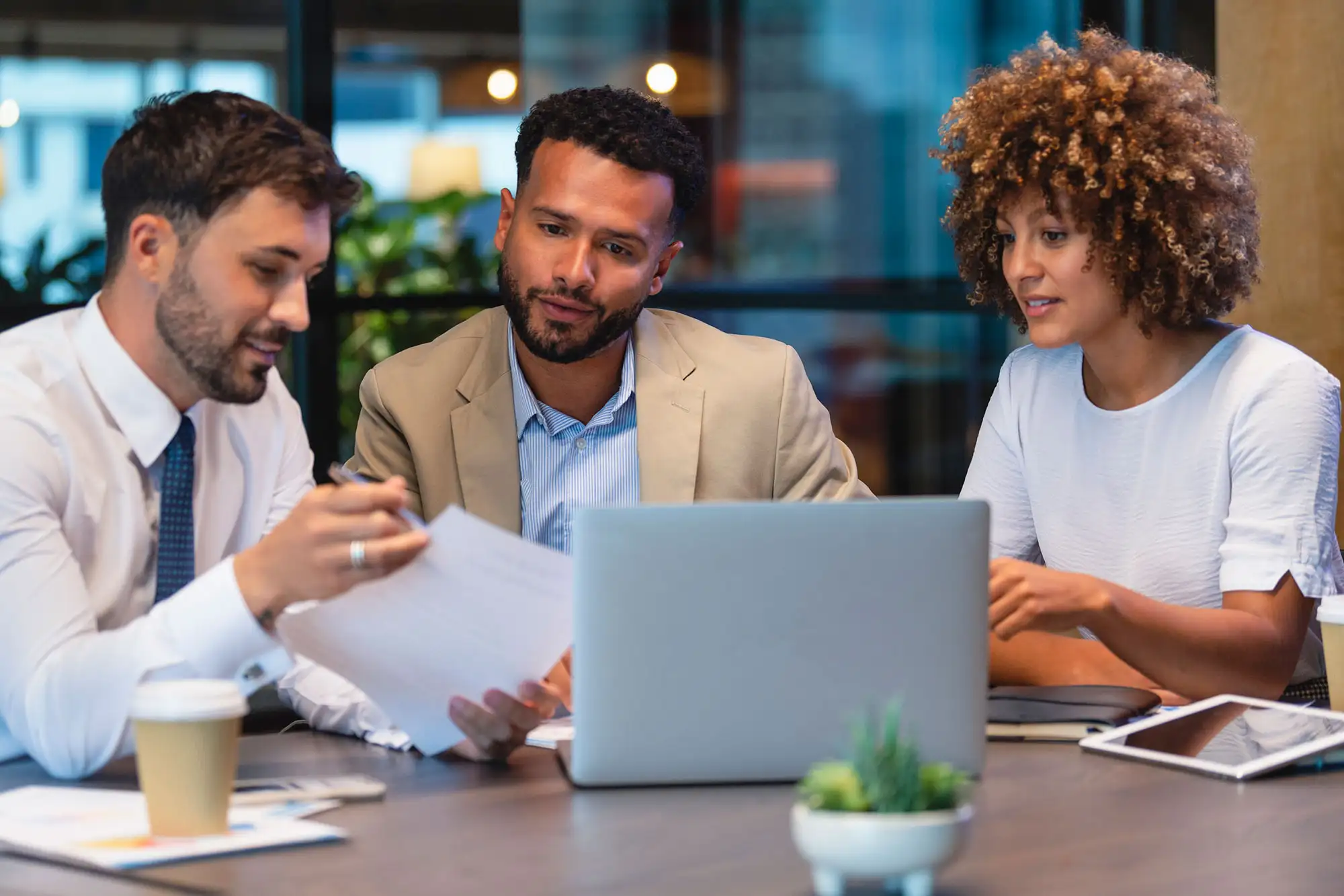 Three professionals collaborating with laptop and documents