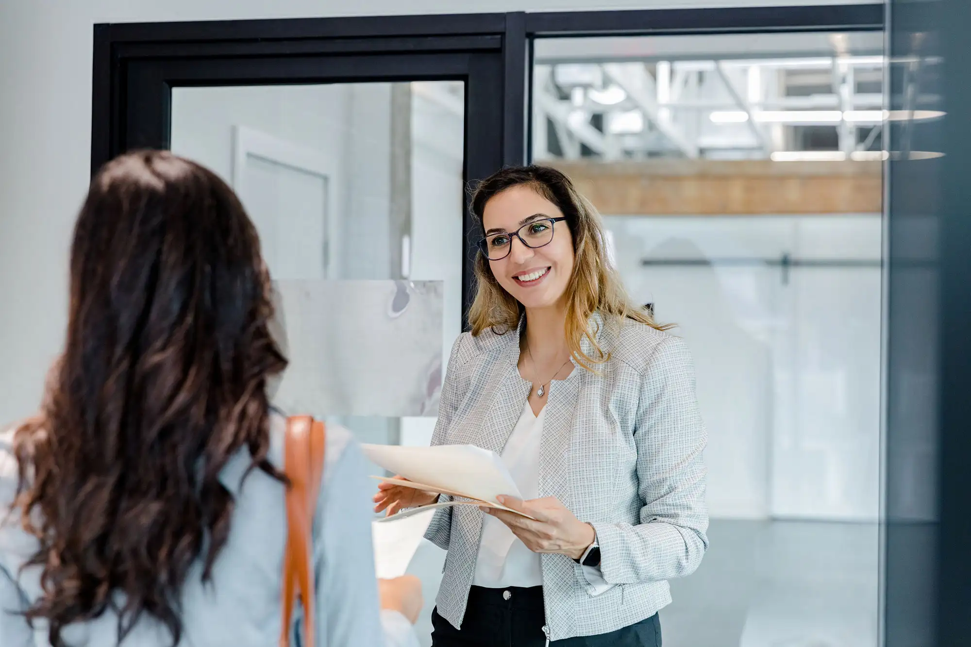 Smiling businesswoman with glasses holding documents in office