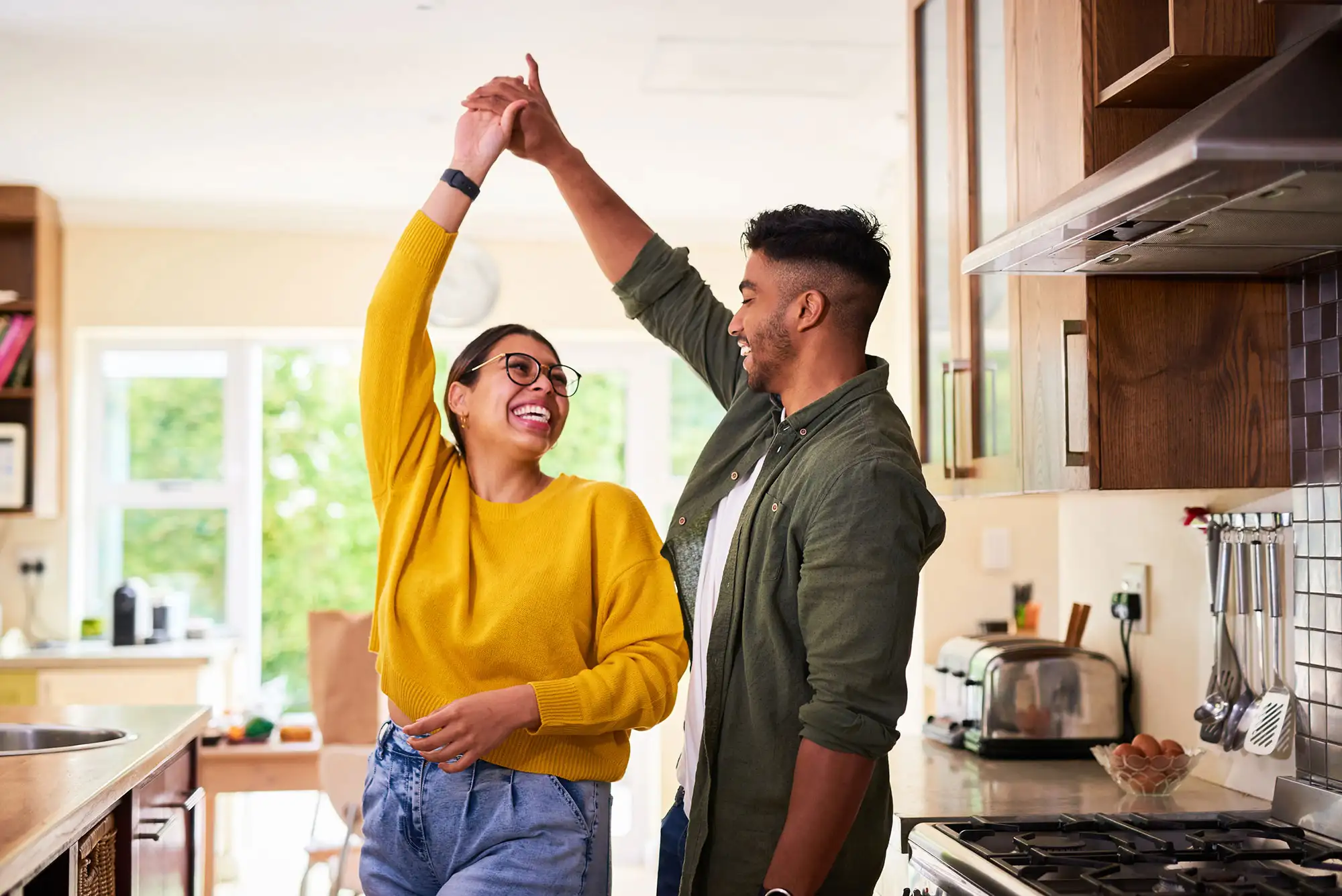Happy couple dancing together in a bright home kitchen